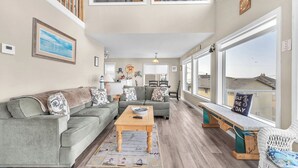 A spacious living room with a high ceiling, a dining area, and large windows offering a view of the neighborhood. - Sweeping ocean views for your families getaway with easy access to great beaches (Lincoln City)