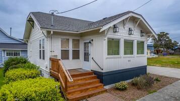 A single-story house with a front porch, a set of wooden steps, and a small garden area.