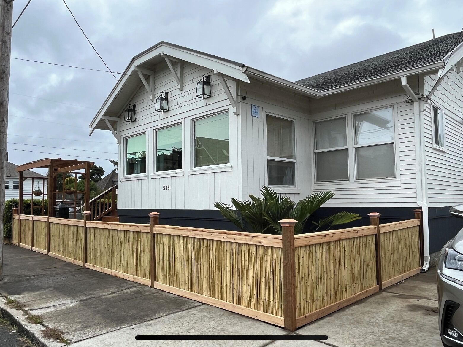 A white two-story house with a wooden fence, a covered porch, and a garage.