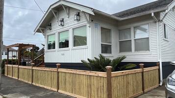 A white two-story house with a wooden fence, a covered porch, and a garage.