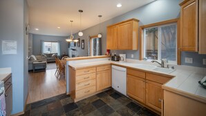 A modern kitchen with wooden cabinets, a dishwasher, and a large window.
