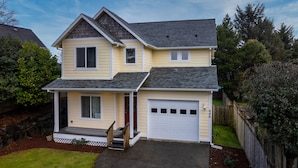 A two-story house with a front porch, a garage, and a well-maintained lawn.