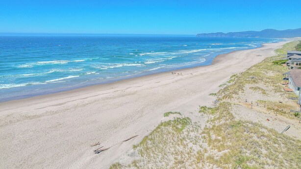 Ein Strand mit Sandküste und einem Haus auf der rechten Seite.