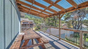Eine überdachte Terrasse mit Holztisch und Metallgeländer.