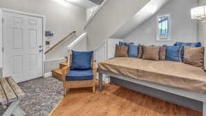 Ein gemütliches Zimmer mit Bett, Stuhl, Treppe und Tür.