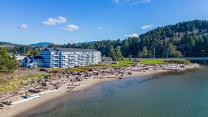 Un hotel costero con un edificio grande, una playa de arena y una colina boscosa al fondo.