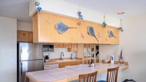 Una cocina con armarios de madera, un refrigerador de acero inoxidable, un fregadero y una zona de comedor con mesa y sillas.