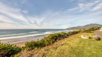 A coastal landscape with a grassy area, a stone structure, and a view of the ocean.