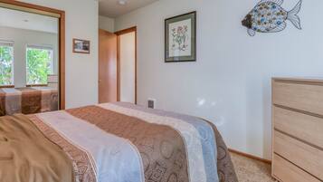 Un dormitorio con cama, cómoda, espejo y un detalle decorativo de pez en la pared.