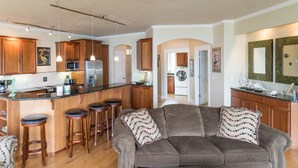 Una cocina moderna con armarios de madera, una isla central con taburetes, un refrigerador y un microondas.