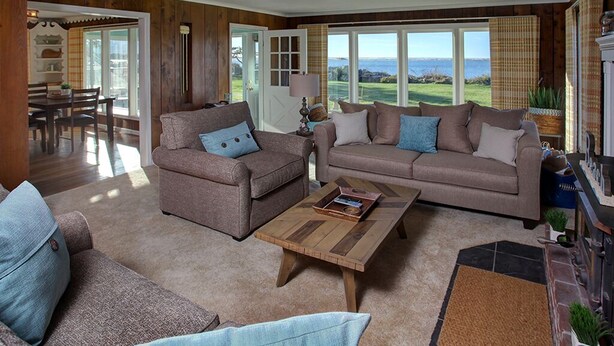 A spacious living room with two sofas, a coffee table, and a view of the outdoors. - Enjoy Riverfront Views from the Porch, short drive to Beach and Promenade (Seaside)
