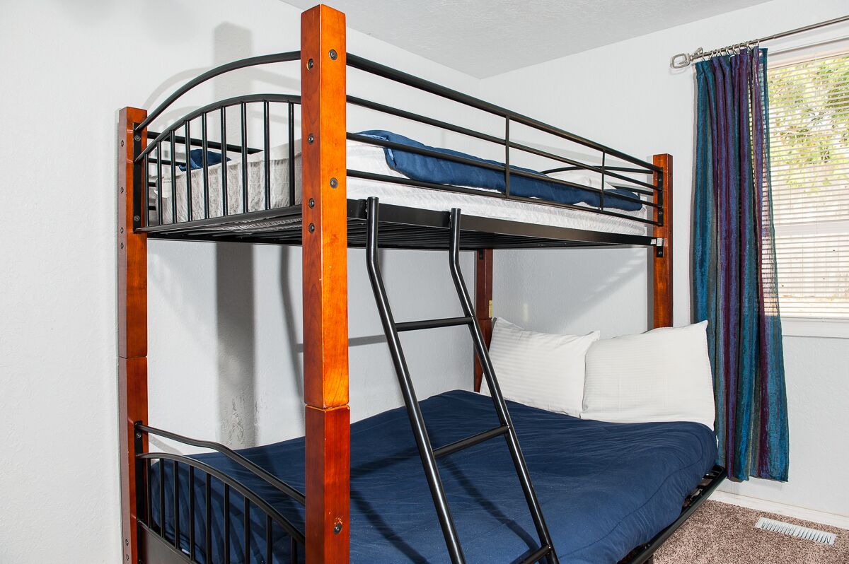 A bunk bed with a wooden frame and metal railings, a blue mattress, and white pillows.