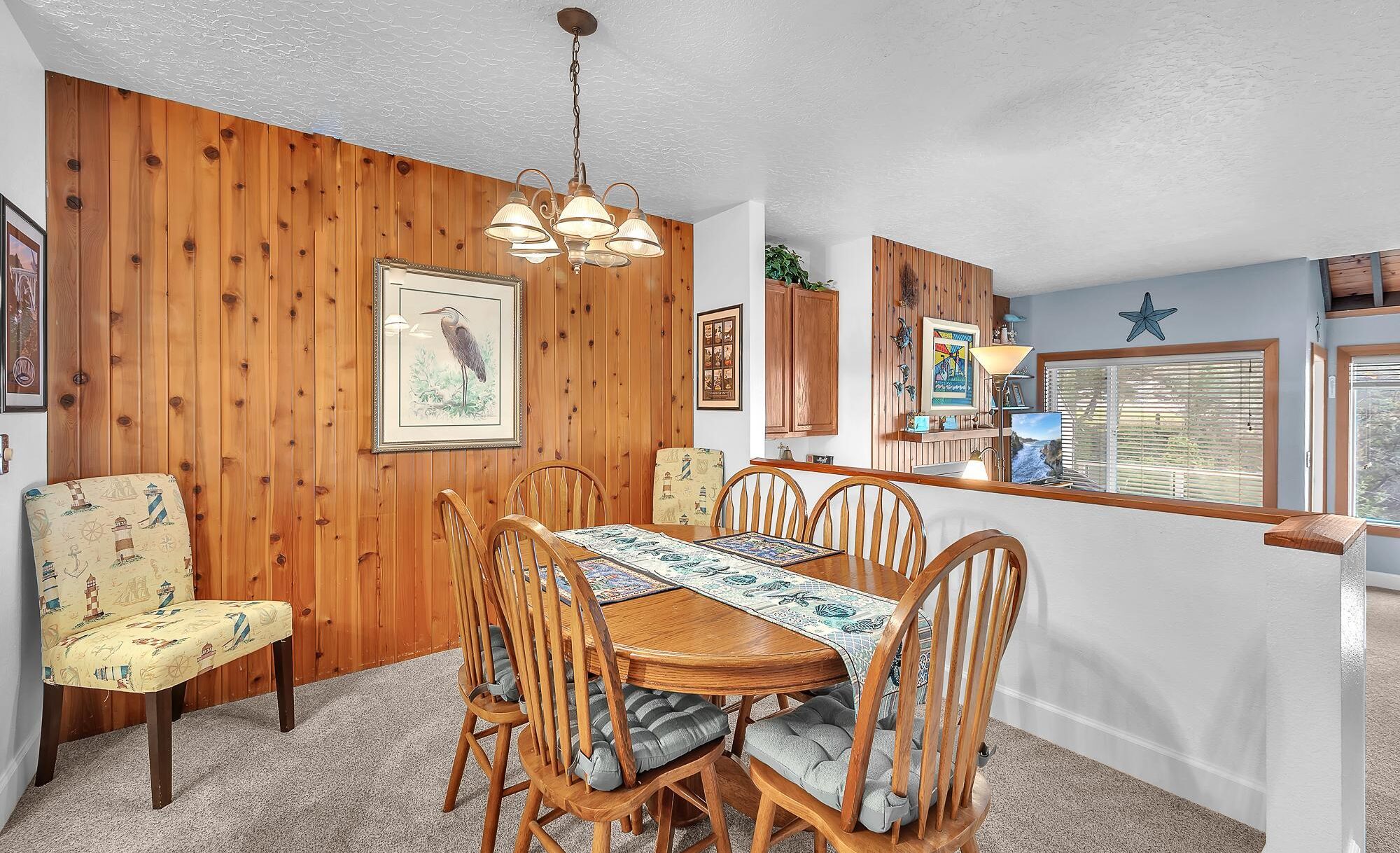 A dining area with a wooden table, chairs, and a ceiling light fixture.