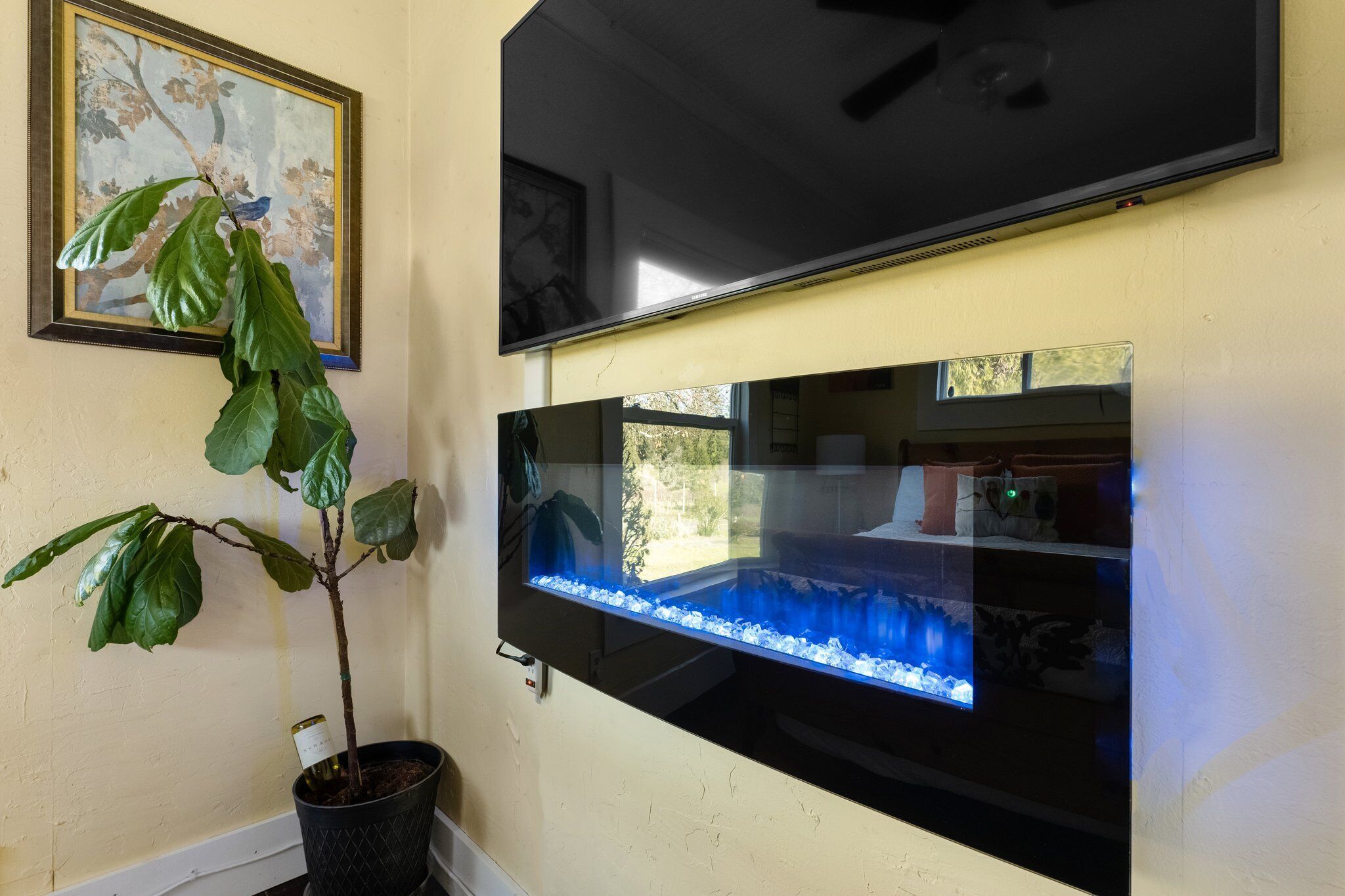 Une pièce dotée d’un grand téléviseur à écran plat fixé au mur, d’une plante en pot et d’un aquarium.