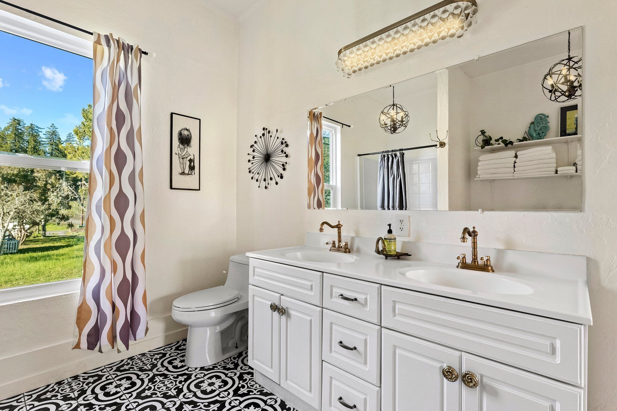 A bathroom with a white vanity, a large mirror, a toilet, and a patterned floor.