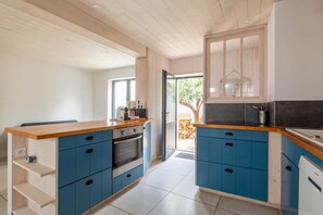 Eine moderne Küche mit blauen Schränken, Holz Arbeitsplatten und einem eingebauten Backofen.