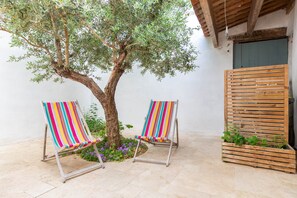 Two striped beach chairs, a tree, and a wooden planter with plants.