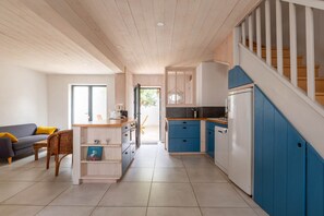Eine moderne Küche mit blauen Schränken, einer Holztreppe und einem Essbereich mit einer Couch und einem Sessel.