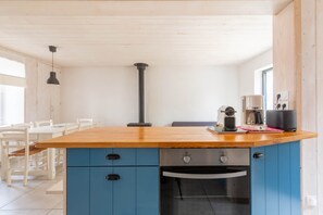 Een moderne keuken met een houten aanrecht, blauwe kastjes, een inbouwoven en een koffieapparaat.