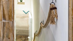 A hallway with a wooden-framed view into another room, a wall-mounted rope toy, and a small plant on a shelf. - B&B Fico d'India (Polignano a Mare)
