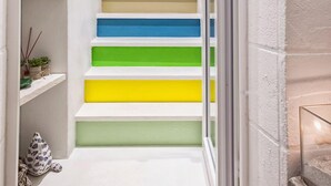 A narrow hallway with a staircase featuring alternating white and colorful steps. - B&B Fico d'India (Polignano a Mare)