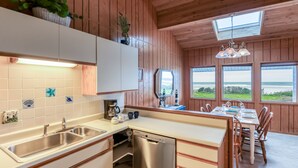 Een moderne keuken met een vaatwasser, een spoelbak en een eethoek met een tafel en stoelen.