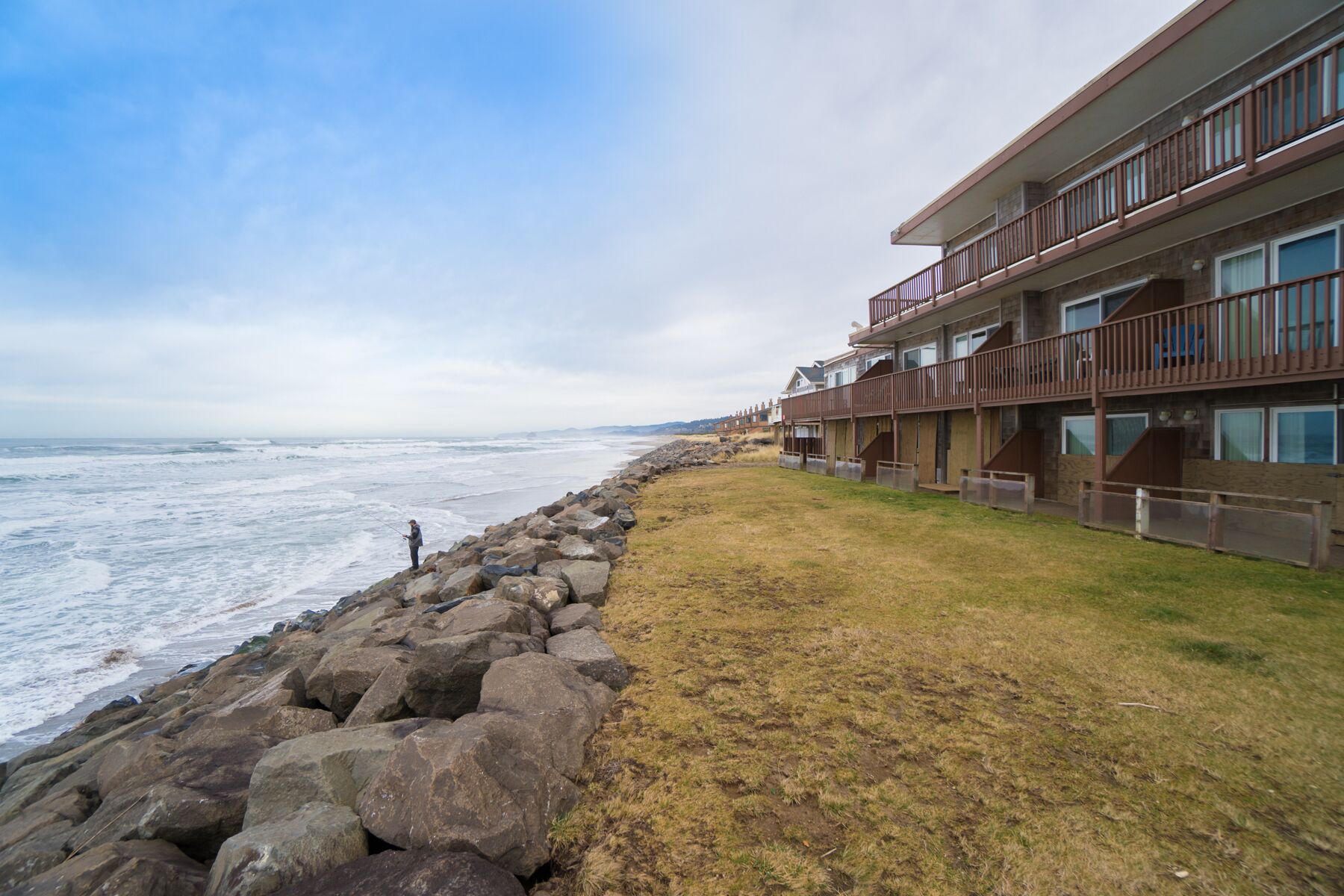 Un hôtel situé sur la côte, avec un rivage rocheux, une zone herbeuse et une vue sur l’océan.