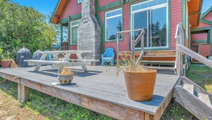 Une terrasse en bois avec une table de pique-nique, des plantes en pot et des sièges d’extérieur.