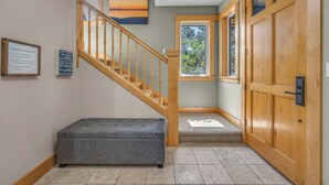 Un escalier en bois menant à un palier où se trouvent un banc et une porte.