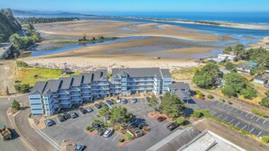 Een kusthotel met meerlaagsgebouwen, een parkeerplaats en uitzicht op het strand.