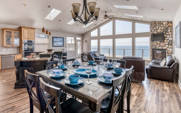 A spacious dining area with a large table set for six, overlooking a scenic ocean view.