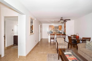 Relax in this open-plan living space with a dining table, sofa, and kitchen area featuring a stove, sink, and microwave.