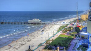 A beach with a pier, a boardwalk, and a roller coaster.