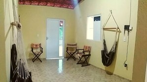 A spacious room with a tiled floor, a hammock, and foldable chairs. - Casa na praia do preá (Cruz)