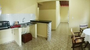 A compact kitchen with a microwave, toaster, and sink. There is a dining area with a round table and chairs. - Casa na praia do preá (Cruz)
