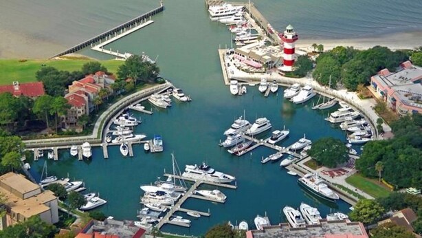 Luftaufnahme einer Marina mit mehreren Stegen, Booten und einem Leuchtturm.