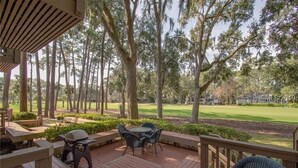 Eine Holzterrasse mit Sitzgelegenheiten im Freien mit Blick auf einen Golfplatz.