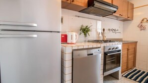 Une cuisine de taille réduite, avec un réfrigérateur blanc, un lave-vaisselle, une cuisinière et des armoires en bois.