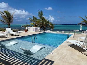 A swimming pool with lounge chairs and a view of the ocean.