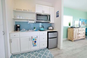 A compact kitchen with white cabinets, a microwave, a coffee maker, and a dishwasher. - Starfish at The Cottages | Breakfast Included (East End)