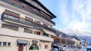 Un hôtel à plusieurs étages, doté de balcons, d’une façade en pierre et surplombant un paysage montagneux.