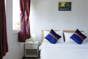 A hotel room with a bed, a nightstand, a lamp, and a painting on the wall.
