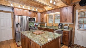 A kitchen with wooden cabinets, stainless steel appliances, and a granite countertop. - Mountain Cabin with Access to Lakes & Waterfalls (Seven Devils)