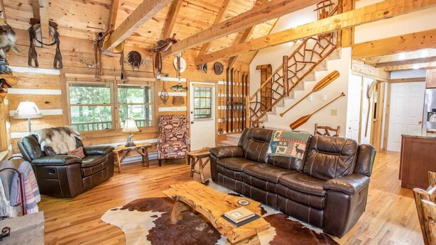 A rustic cabin interior with wooden beams, leather furniture, and a cowhide rug. - Mountain Cabin with Access to Lakes & Waterfalls (Seven Devils)