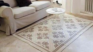A living room with a beige sofa, a small white coffee table, and a patterned rug.