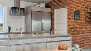 Una cucina moderna con una grande isola, elettrodomestici in acciaio inossidabile e una parete in mattoni.