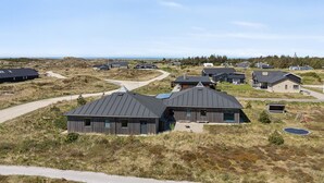 Un quartiere residenziale con case moderne, cielo sereno e un percorso che conduce al mare.