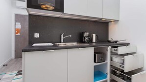 A modern kitchen with a black countertop, stainless steel appliances, and white cabinets. - Cracow | Rajska 3 | Modern Studio | Air conditioning (Kraków)