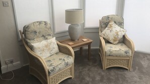 Two wicker armchairs with floral upholstery, a small wooden side table, and a lamp. - 100 meters from the beach, Charming coastal period house. (Kingsdown Deal)