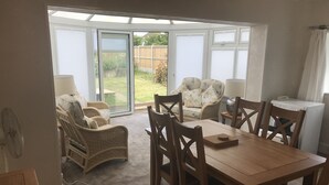 A dining area with a table and chairs, a sofa, and a sliding glass door leading to a garden. - 100 meters from the beach, Charming coastal period house. (Kingsdown Deal)